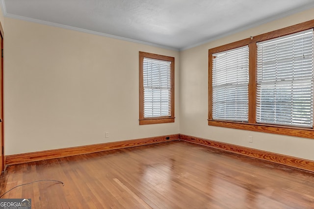 spare room with hardwood / wood-style flooring and crown molding