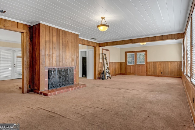 unfurnished living room with ornamental molding, light colored carpet, and wood walls