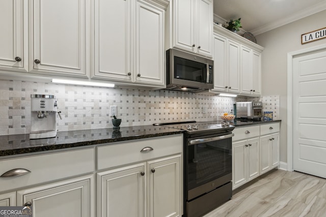 kitchen with tasteful backsplash, white cabinetry, dark stone countertops, ornamental molding, and stainless steel appliances