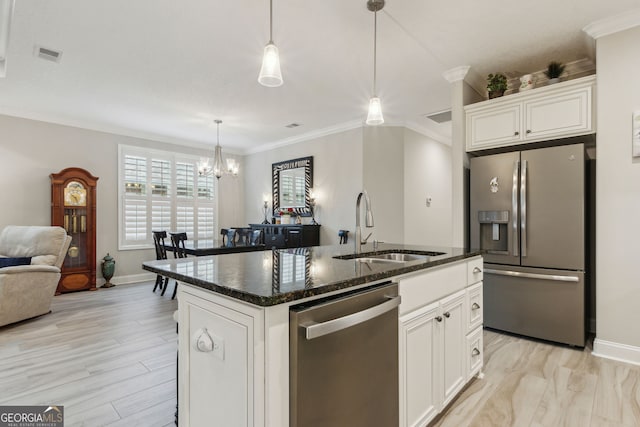 kitchen with decorative light fixtures, white cabinetry, sink, stainless steel appliances, and a center island with sink