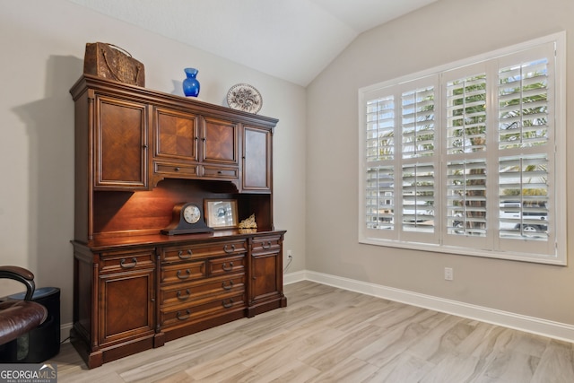 office with lofted ceiling, a wealth of natural light, and light hardwood / wood-style flooring