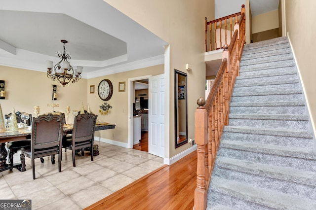 tiled dining space with crown molding, a tray ceiling, and a chandelier