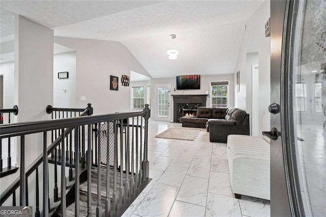 corridor with lofted ceiling and a textured ceiling