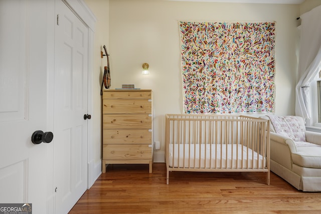 bedroom with a closet, hardwood / wood-style flooring, and a nursery area