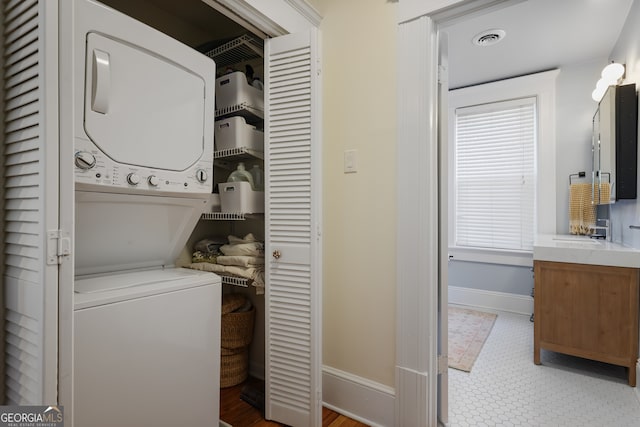 clothes washing area with stacked washer / drying machine and sink