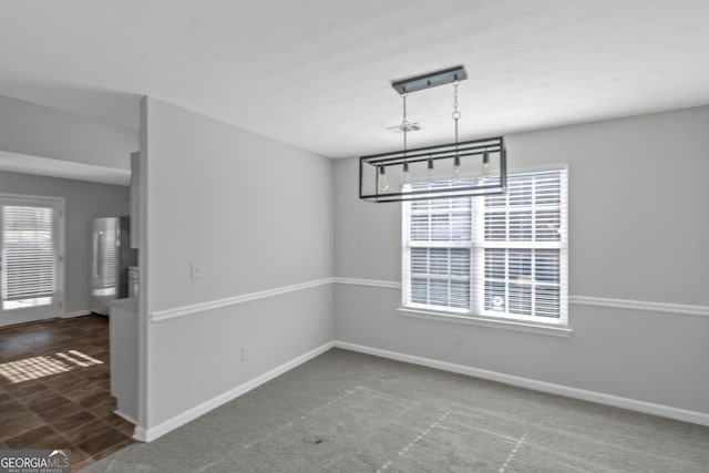 unfurnished dining area featuring dark colored carpet and a notable chandelier