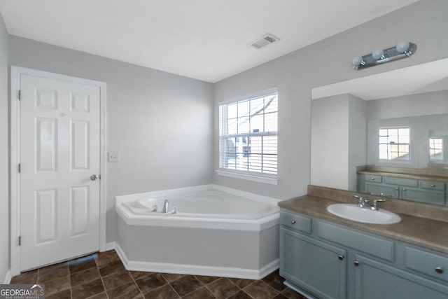 bathroom with tile patterned flooring, vanity, and a tub to relax in