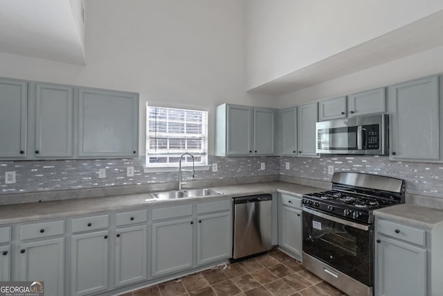 kitchen featuring appliances with stainless steel finishes, sink, decorative backsplash, and gray cabinetry