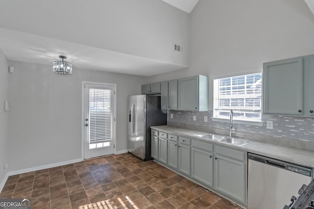 kitchen featuring tasteful backsplash, sink, gray cabinetry, a notable chandelier, and stainless steel appliances