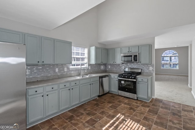 kitchen featuring sink, dark colored carpet, gray cabinets, stainless steel appliances, and backsplash