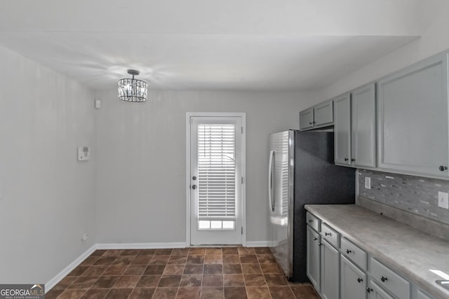 kitchen with pendant lighting, a notable chandelier, decorative backsplash, and gray cabinets