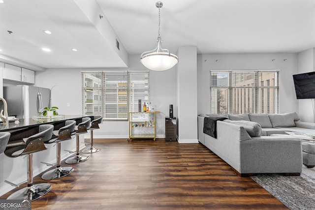 living area with dark wood-style floors, plenty of natural light, recessed lighting, and baseboards