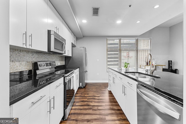 kitchen with dark wood-style floors, visible vents, a sink, stainless steel appliances, and tasteful backsplash