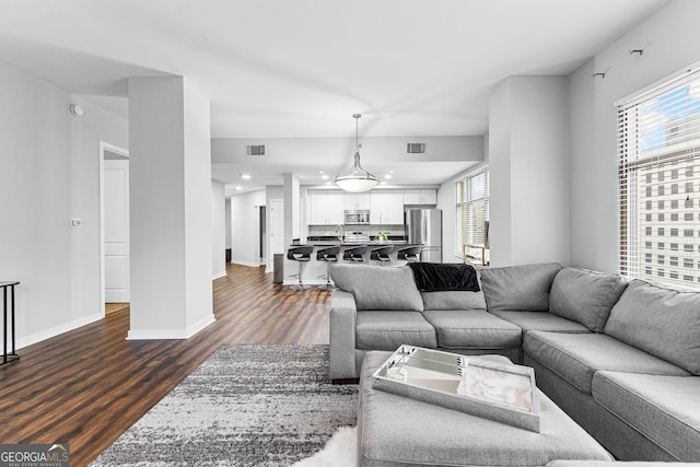 living area featuring visible vents, baseboards, and dark wood-style floors