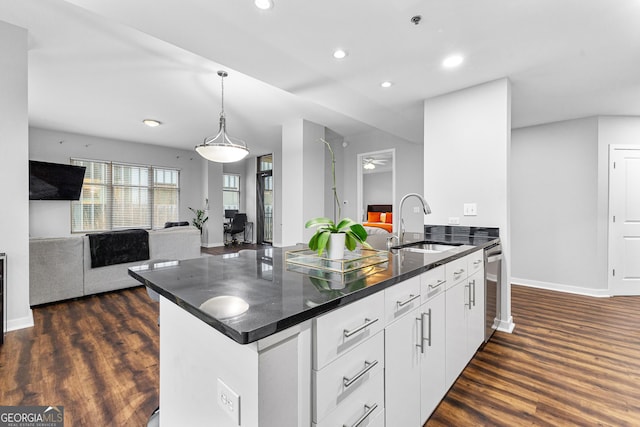 kitchen featuring a sink, dark countertops, open floor plan, and dark wood-style flooring