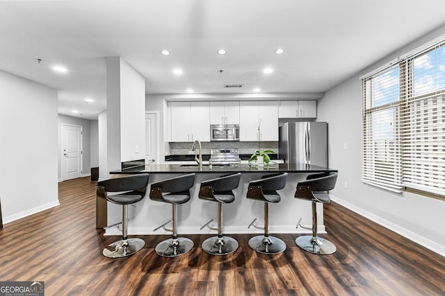 kitchen with dark countertops, a breakfast bar area, appliances with stainless steel finishes, and a sink