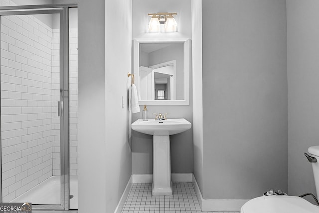 bathroom with tile patterned floors, baseboards, a stall shower, and a sink