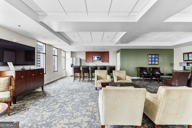 living area featuring a raised ceiling, a drop ceiling, recessed lighting, carpet floors, and baseboards