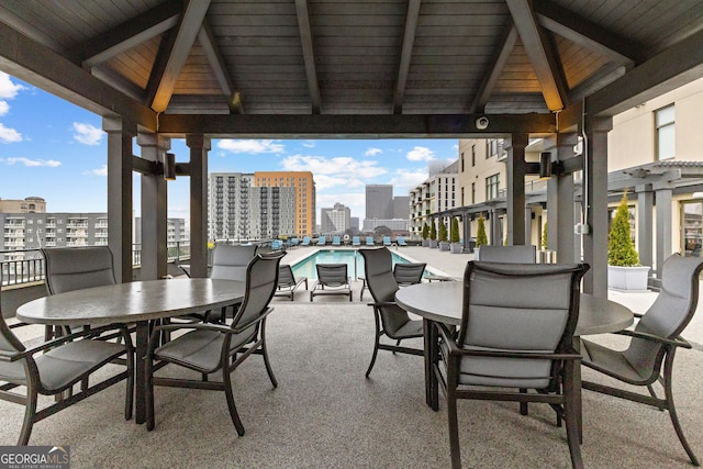 view of patio / terrace with a city view, a gazebo, outdoor dining space, and a community pool