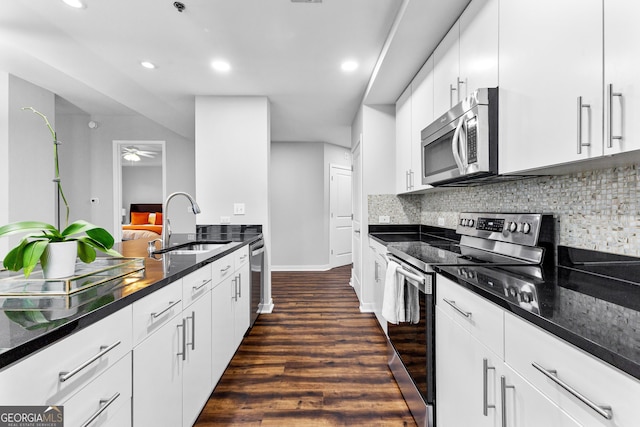 kitchen with dark wood-type flooring, backsplash, appliances with stainless steel finishes, and a sink