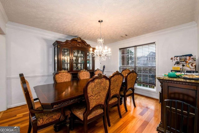 dining room featuring light wood-type flooring, an inviting chandelier, ornamental molding, and a textured ceiling