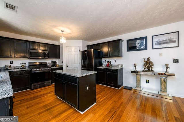 kitchen with stainless steel appliances, visible vents, light stone counters, and dark wood-style floors