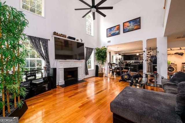 living room featuring plenty of natural light, visible vents, washer / clothes dryer, wood finished floors, and a fireplace