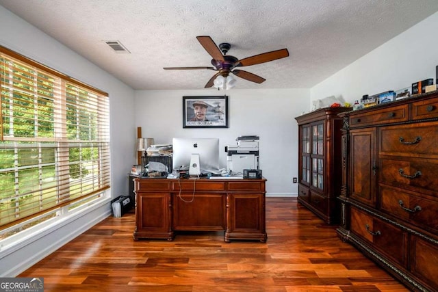 office area with a ceiling fan, a textured ceiling, visible vents, and dark wood-type flooring