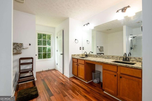 bathroom featuring a stall shower, a sink, a textured ceiling, and wood finished floors