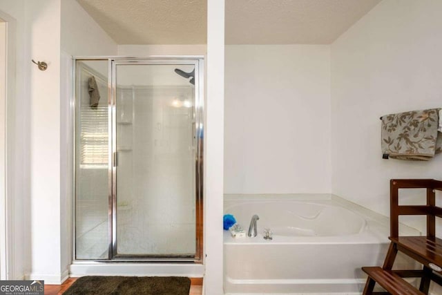 bathroom featuring a textured ceiling, a stall shower, and a bath