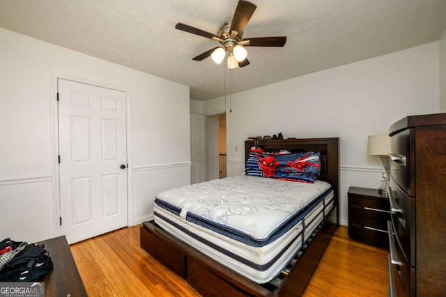 bedroom with a textured ceiling, wood finished floors, and a ceiling fan