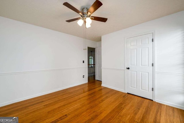 unfurnished bedroom with a textured ceiling, wood finished floors, a ceiling fan, and baseboards