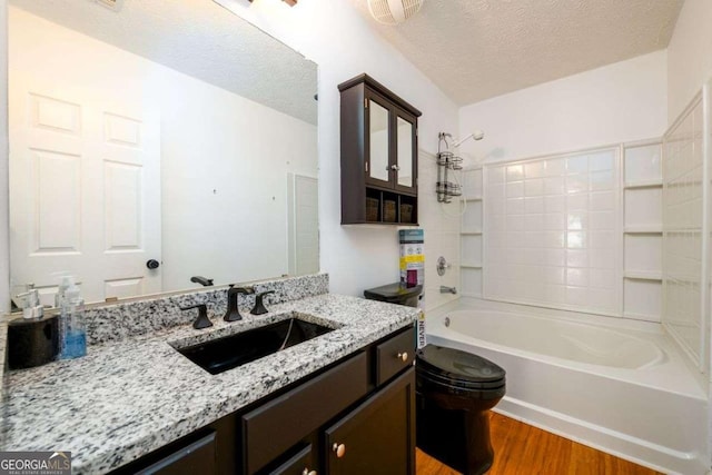 full bathroom featuring tub / shower combination, a textured ceiling, vanity, and wood finished floors