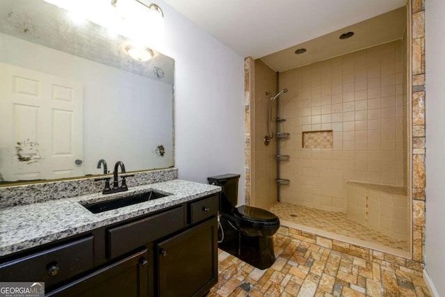 bathroom featuring toilet, a tile shower, and vanity