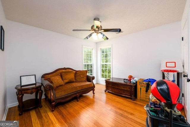 sitting room with a ceiling fan, light wood-type flooring, visible vents, and baseboards