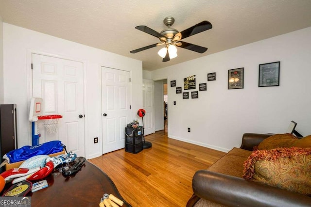 interior space with ceiling fan, light wood finished floors, a textured ceiling, and baseboards