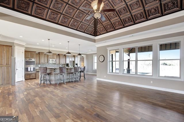 kitchen with appliances with stainless steel finishes, hanging light fixtures, a kitchen breakfast bar, a spacious island, and decorative backsplash