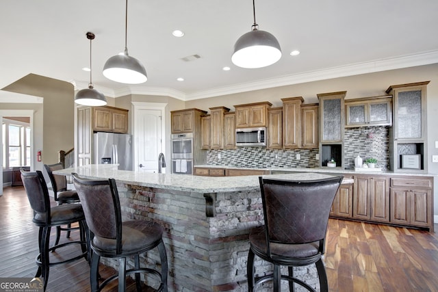 kitchen with a breakfast bar, appliances with stainless steel finishes, hanging light fixtures, a spacious island, and dark hardwood / wood-style flooring