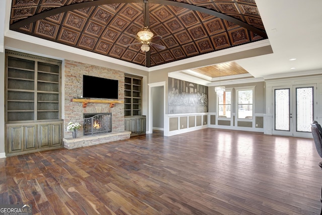 unfurnished living room featuring crown molding, wood-type flooring, built in features, and a large fireplace