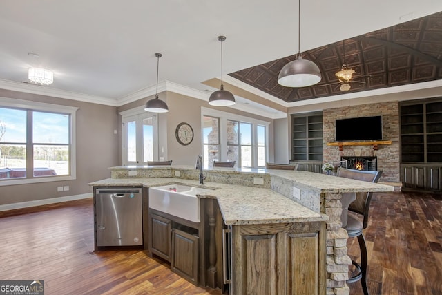 kitchen with a kitchen island with sink, hanging light fixtures, built in shelves, and dishwasher