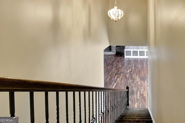 stairs featuring wood-type flooring and an inviting chandelier