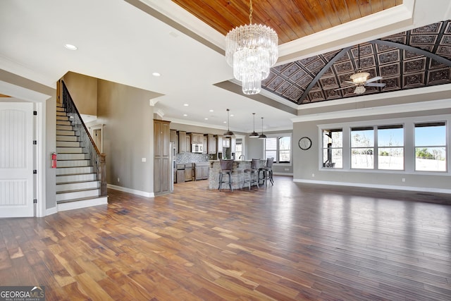 unfurnished living room featuring wood ceiling, an inviting chandelier, dark hardwood / wood-style floors, a tray ceiling, and ornamental molding