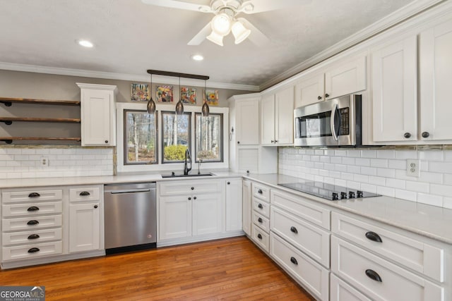 kitchen with sink, appliances with stainless steel finishes, white cabinetry, hanging light fixtures, and ornamental molding