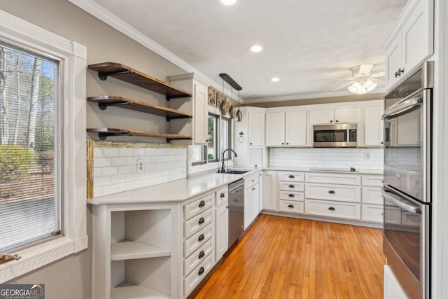 kitchen featuring pendant lighting, white cabinetry, sink, stainless steel appliances, and crown molding