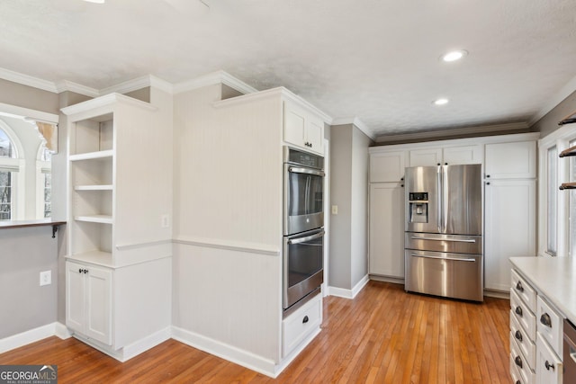 kitchen featuring stainless steel appliances, crown molding, white cabinets, and light hardwood / wood-style flooring