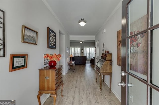 corridor with ornamental molding and light hardwood / wood-style flooring