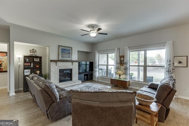 living room with ceiling fan, a fireplace, and light hardwood / wood-style floors