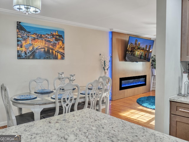 dining space featuring wood finished floors, ornamental molding, and a glass covered fireplace