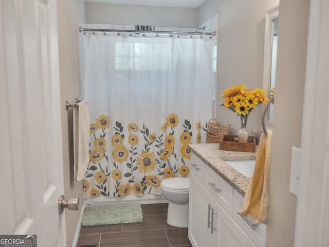 bathroom featuring toilet, shower / bath combo with shower curtain, and vanity