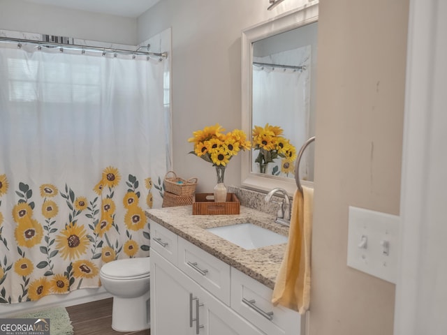 full bath with toilet, shower / bath combo with shower curtain, and vanity